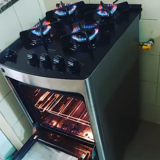 Fogão Consul preto de 4 bocas com forno aquecido e chamas azuis após conserto