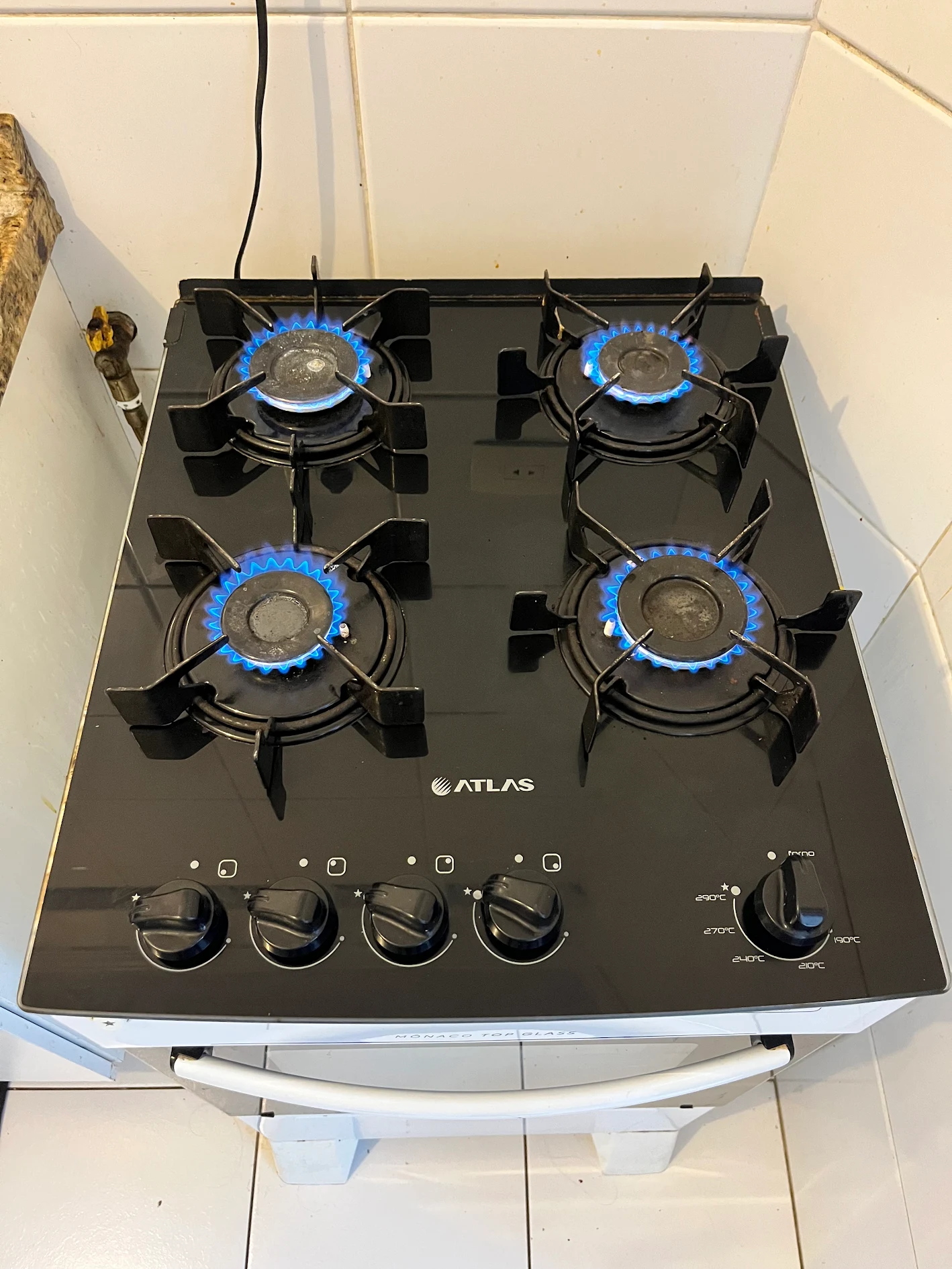 Cooktop Atlas de mesa de vidro com as quatro bocas acesas e chama azul após conserto da JR Fogões
