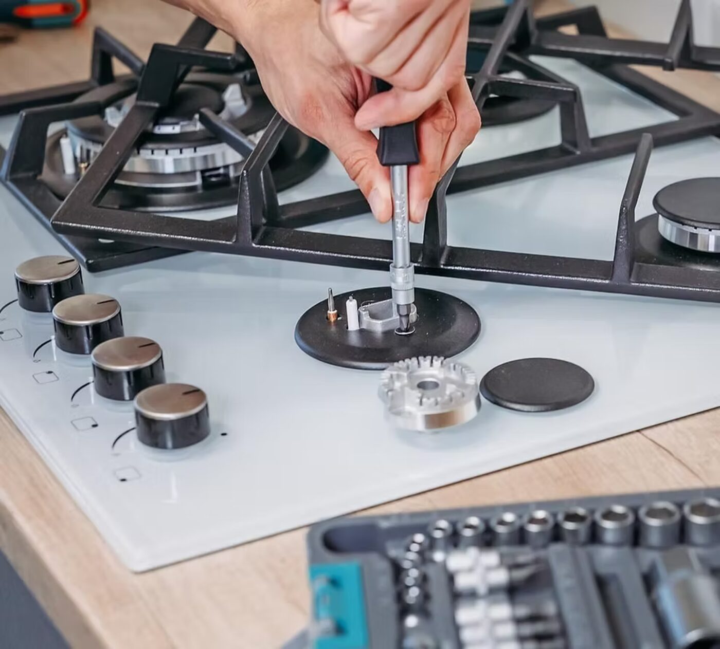 Técnico da JR Fogões desmontando o queimador de um cooktop a gás para troca de peça