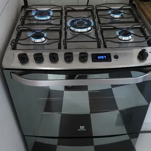 Fogão Electrolux de 5 bocas inox com todas as chamas azuis acesas após manutenção